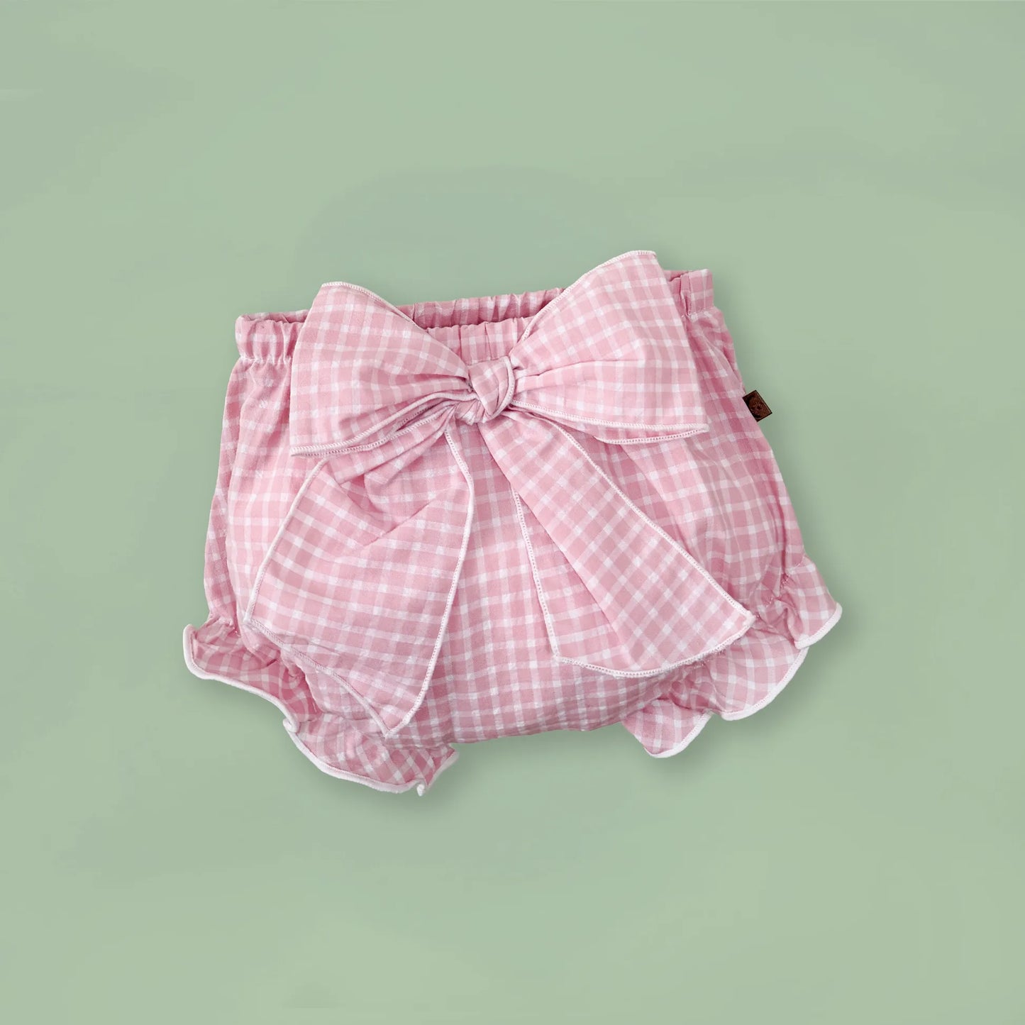 Tapa-fraldas de menina em tecido com laço na frente e folhos rosa