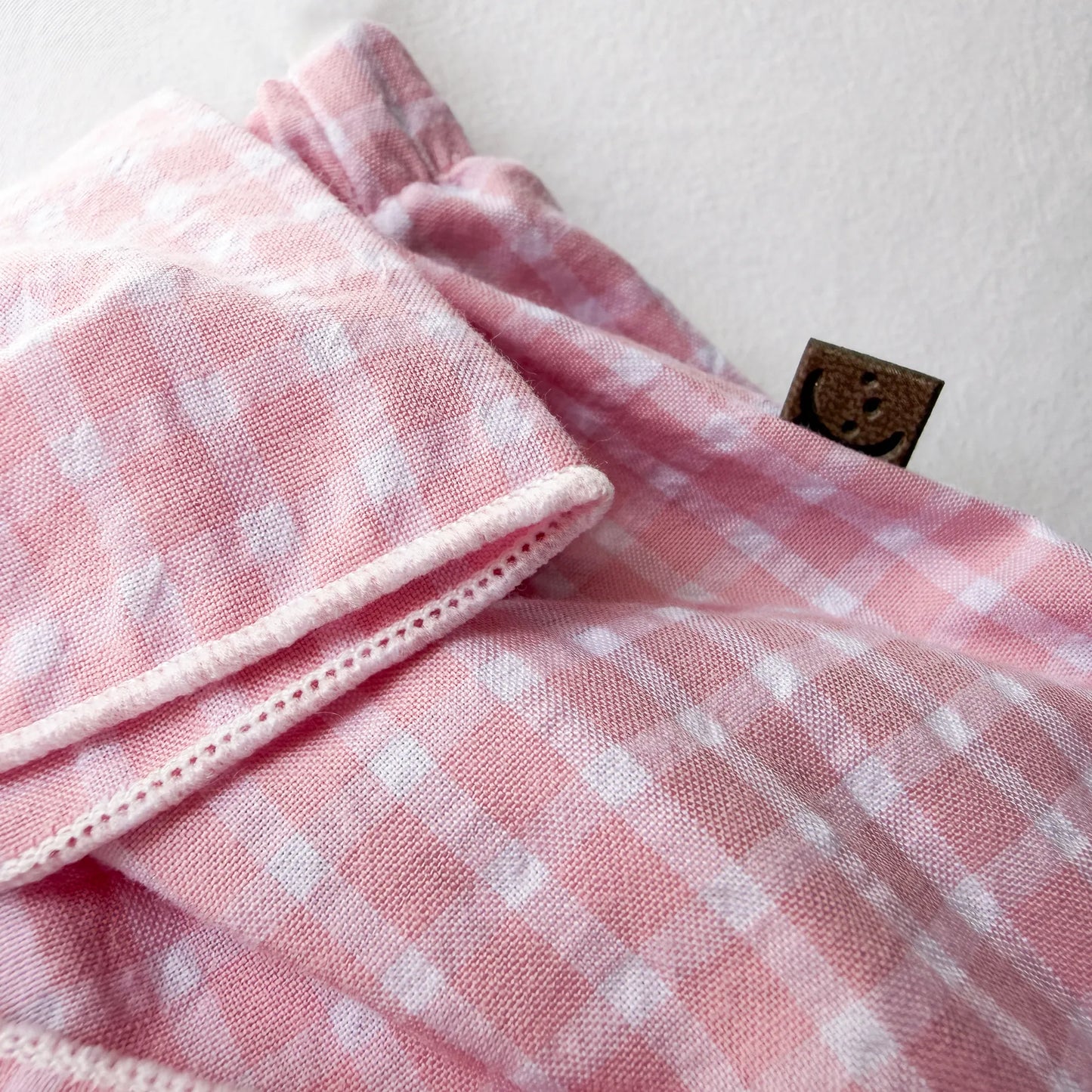 Pormenor de tapa-fraldas de menina em tecido com laço na frente e folhos rosa