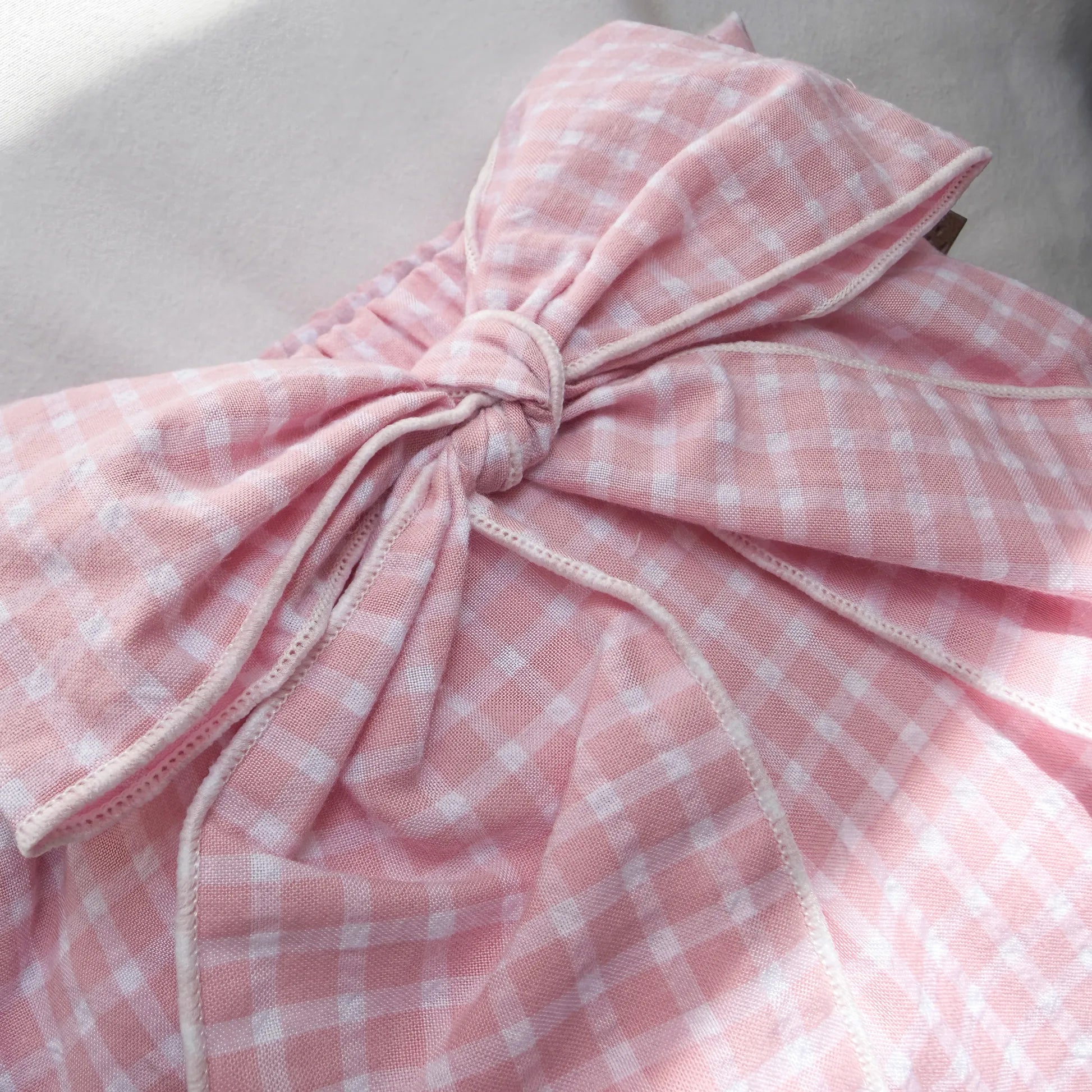 Pormenor de tapa-fraldas de menina em tecido com laço na frente e folhos rosa