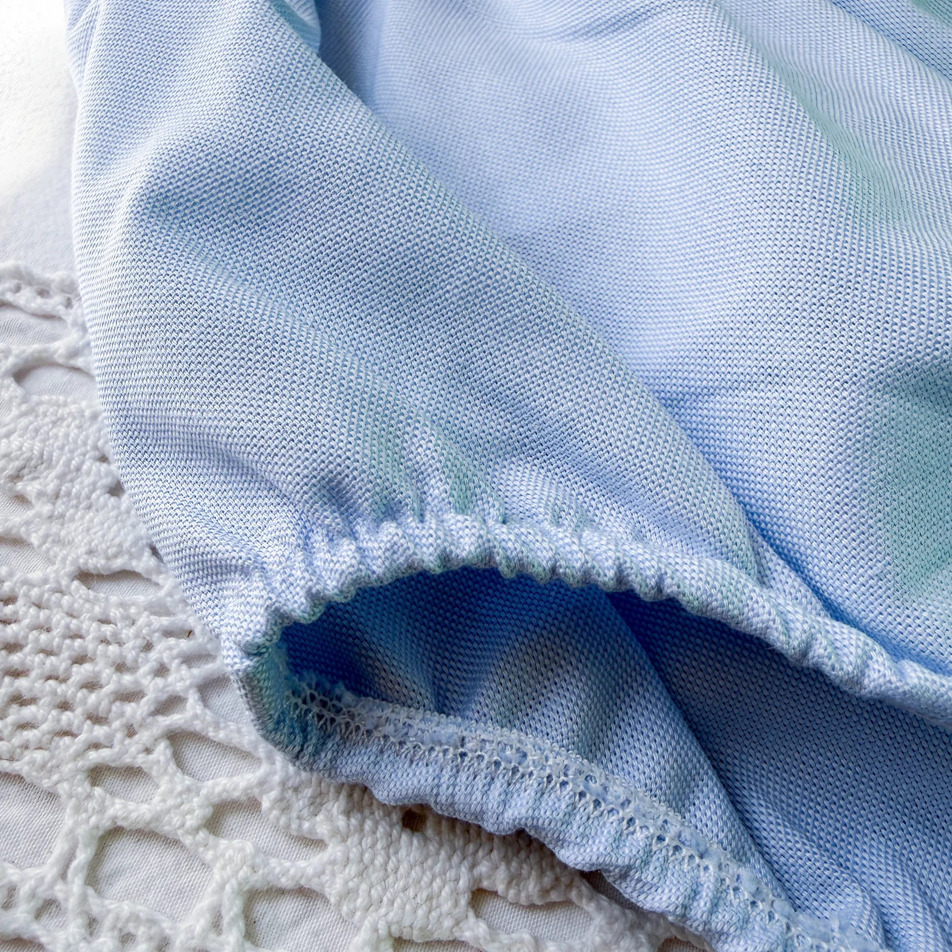 Pormenor de tapa-fraldas em tecido liso com alças azul