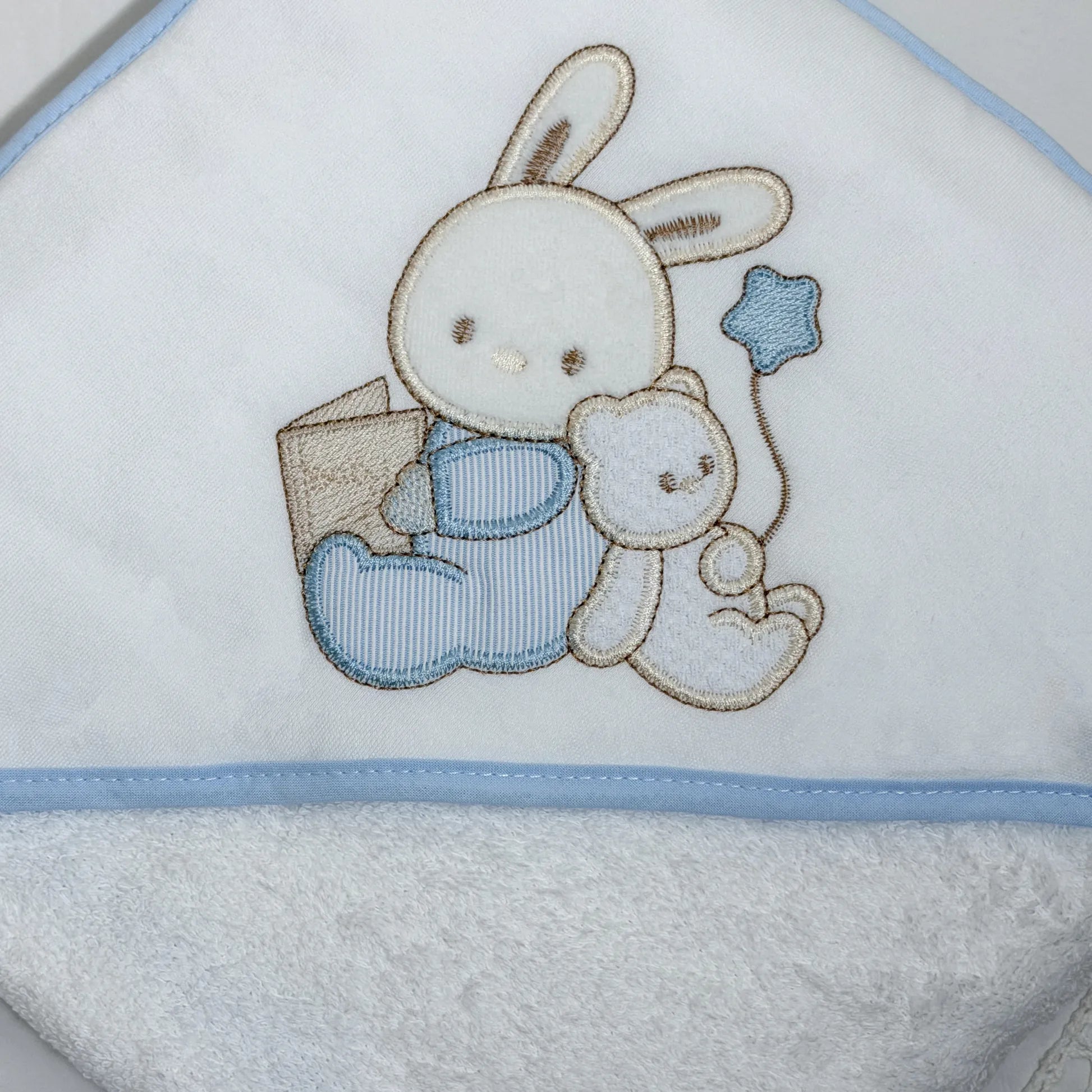 Pormenor de toalha com motivo coelhinho e ursinho com livro azul