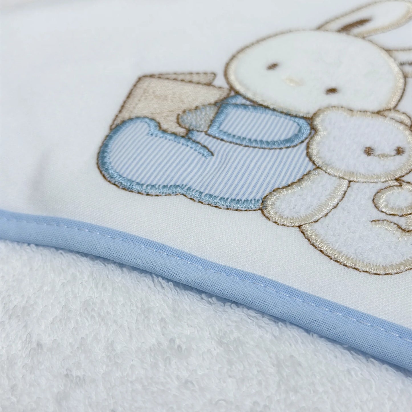 Pormenor de toalha com motivo coelhinho e ursinho com livro azul