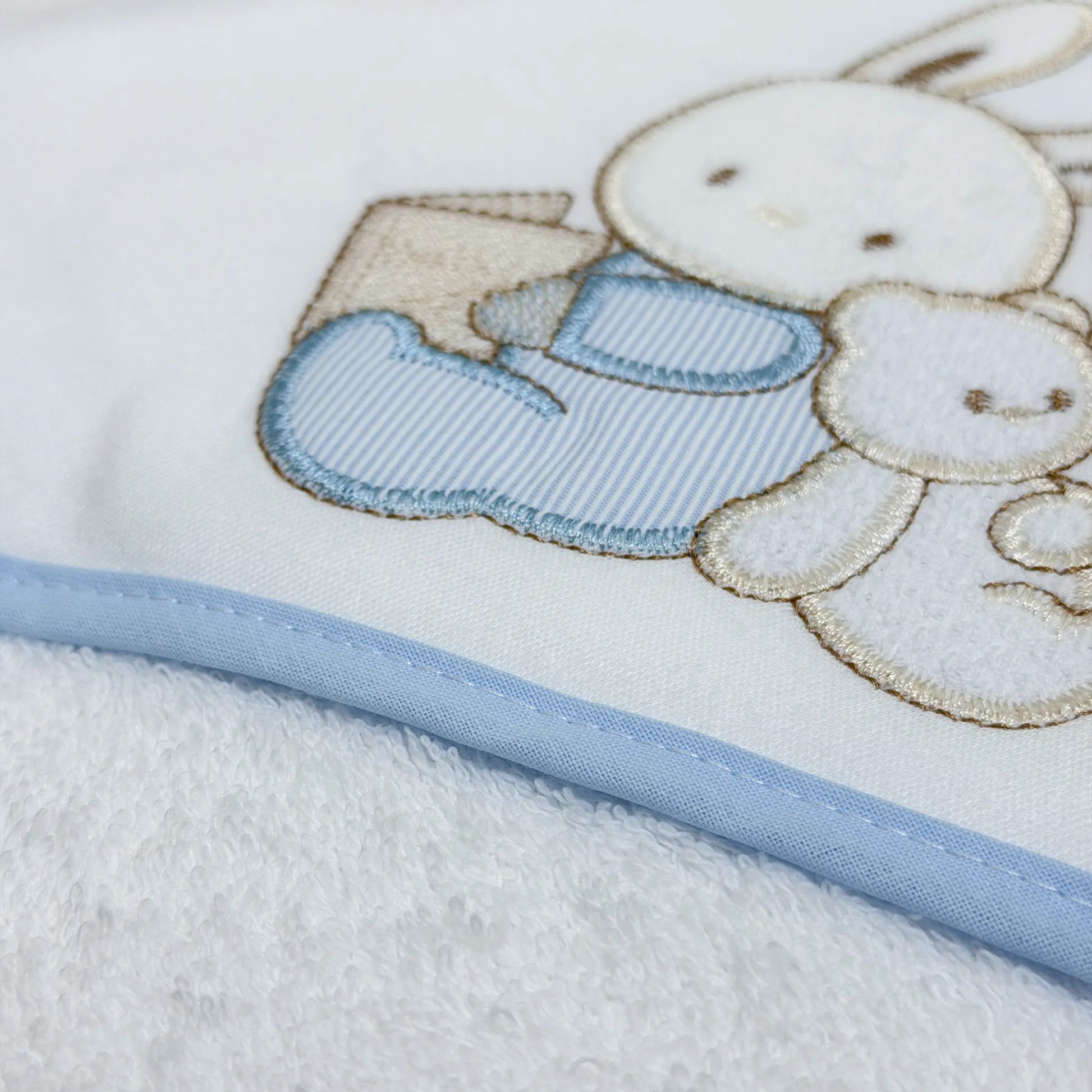 Pormenor de toalha com motivo coelhinho e ursinho com livro azul