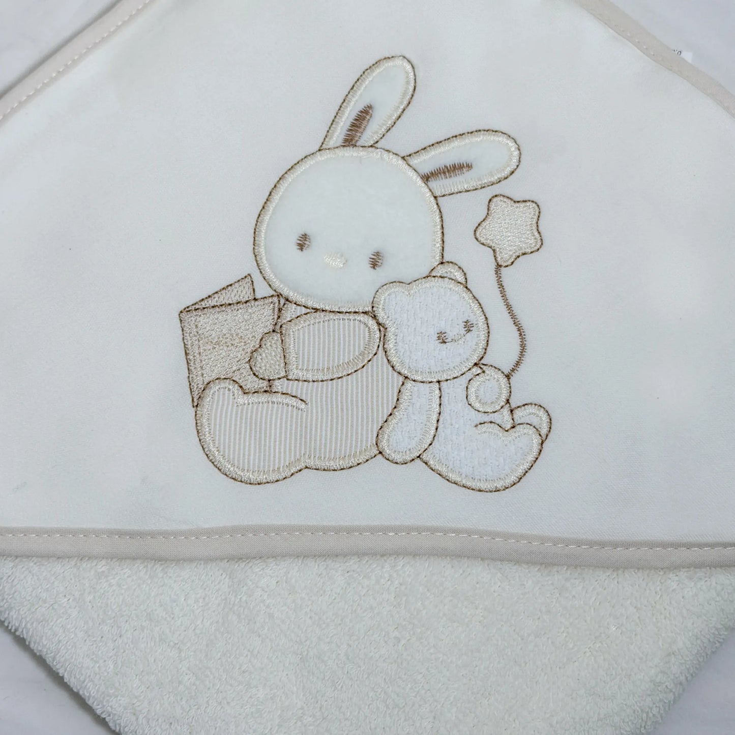 Pormenor de toalha com motivo coelhinho e ursinho com livro pérola