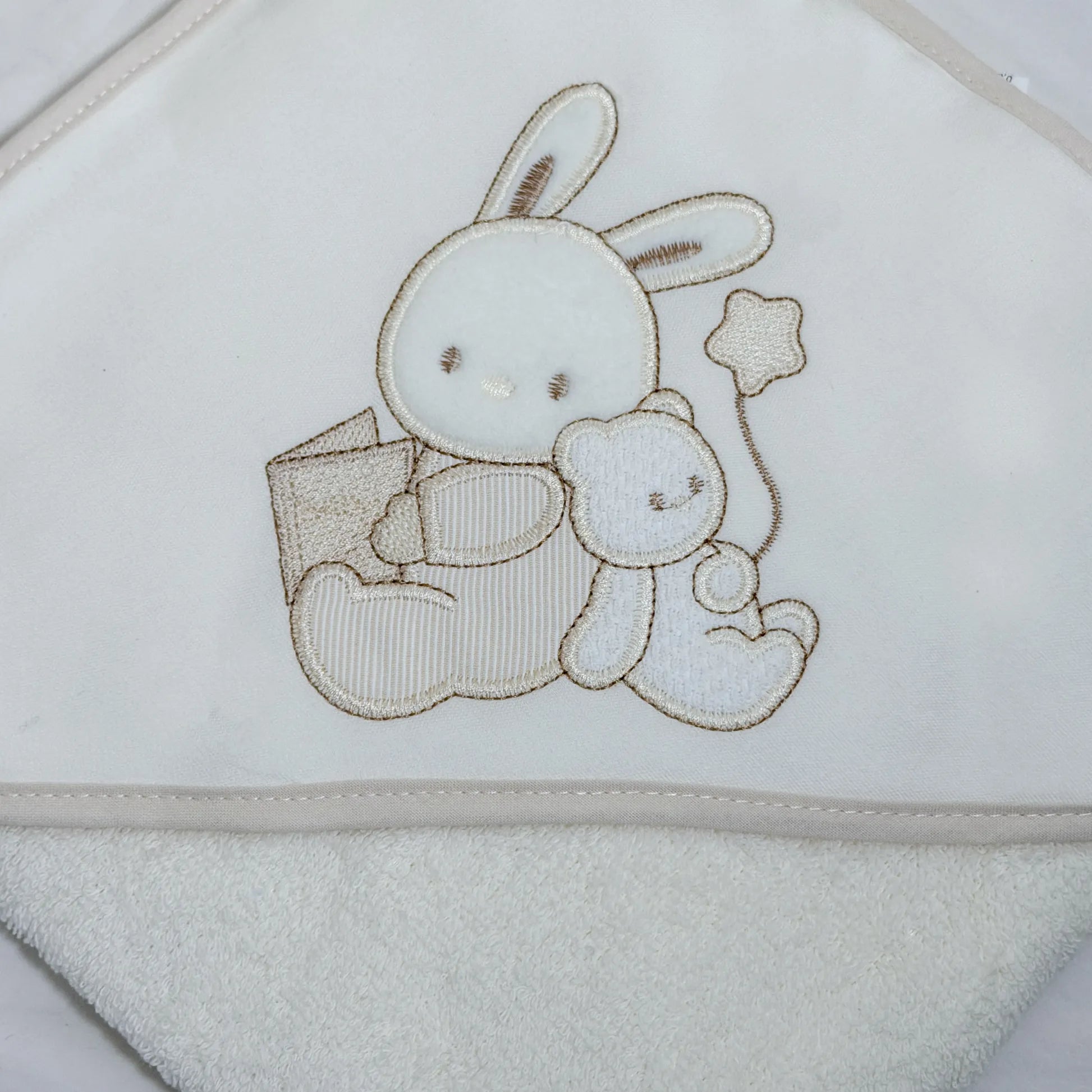 Pormenor de toalha com motivo coelhinho e ursinho com livro pérola