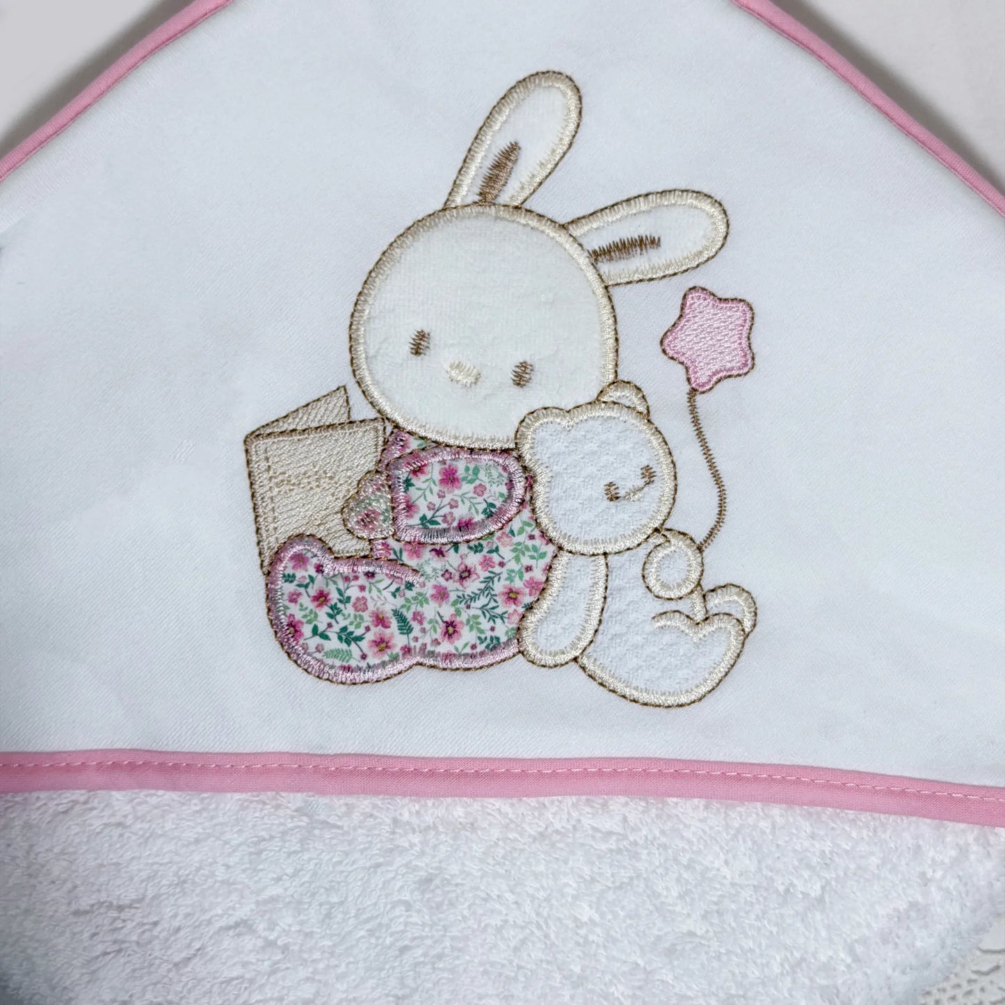Pormenor de toalha com motivo coelhinho e ursinho com livro rosa