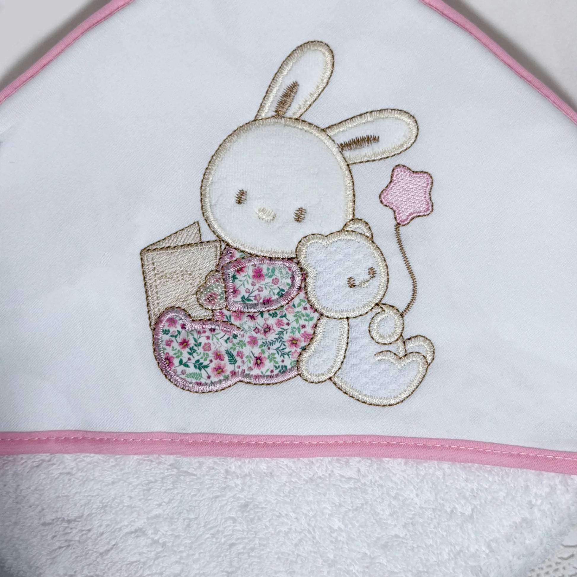 Pormenor de toalha com motivo coelhinho e ursinho com livro rosa