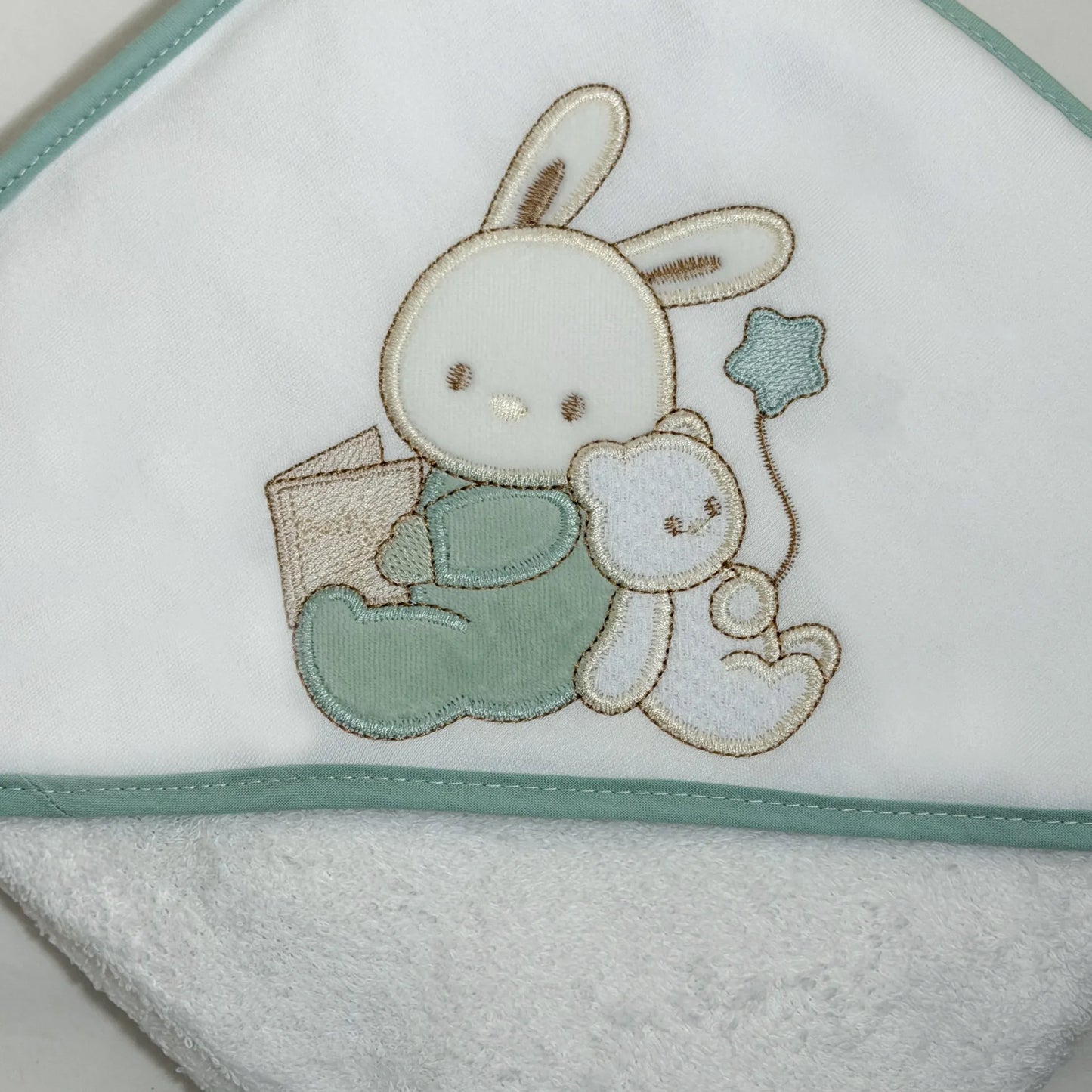 Pormenor de toalha com motivo coelhinho e ursinho com livro verde