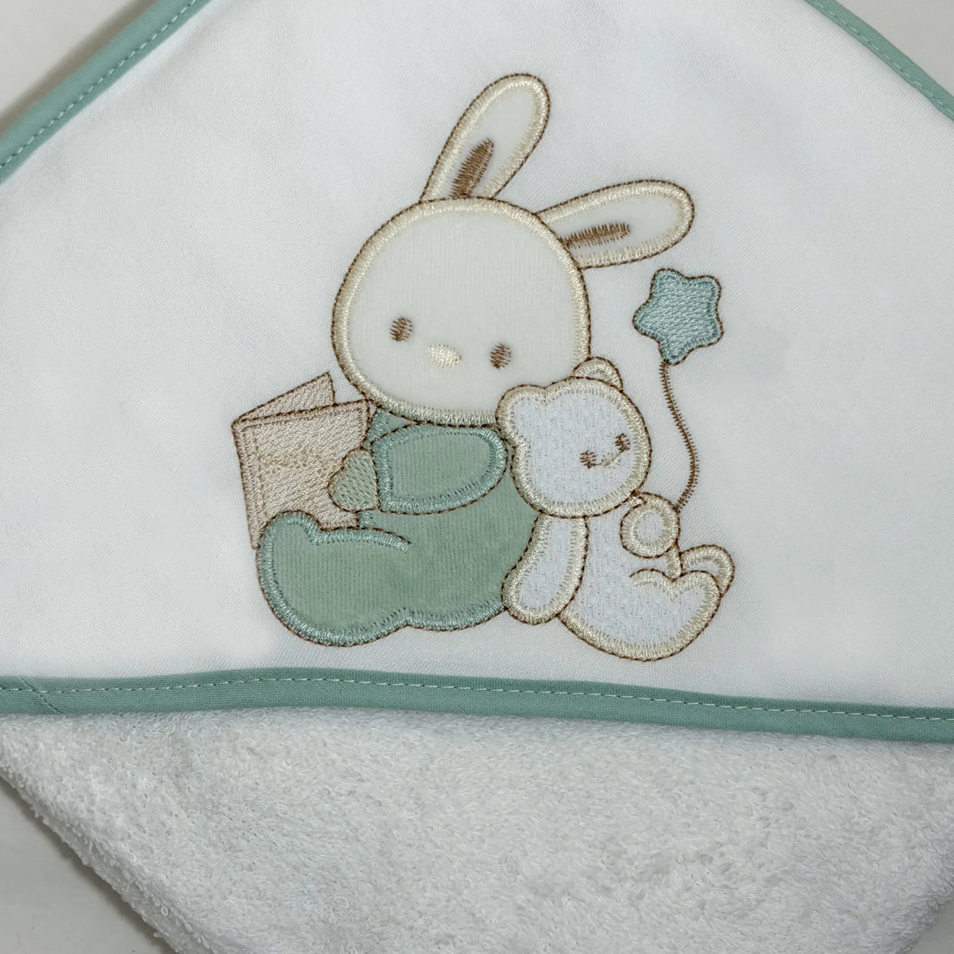 Pormenor de toalha com motivo coelhinho e ursinho com livro verde