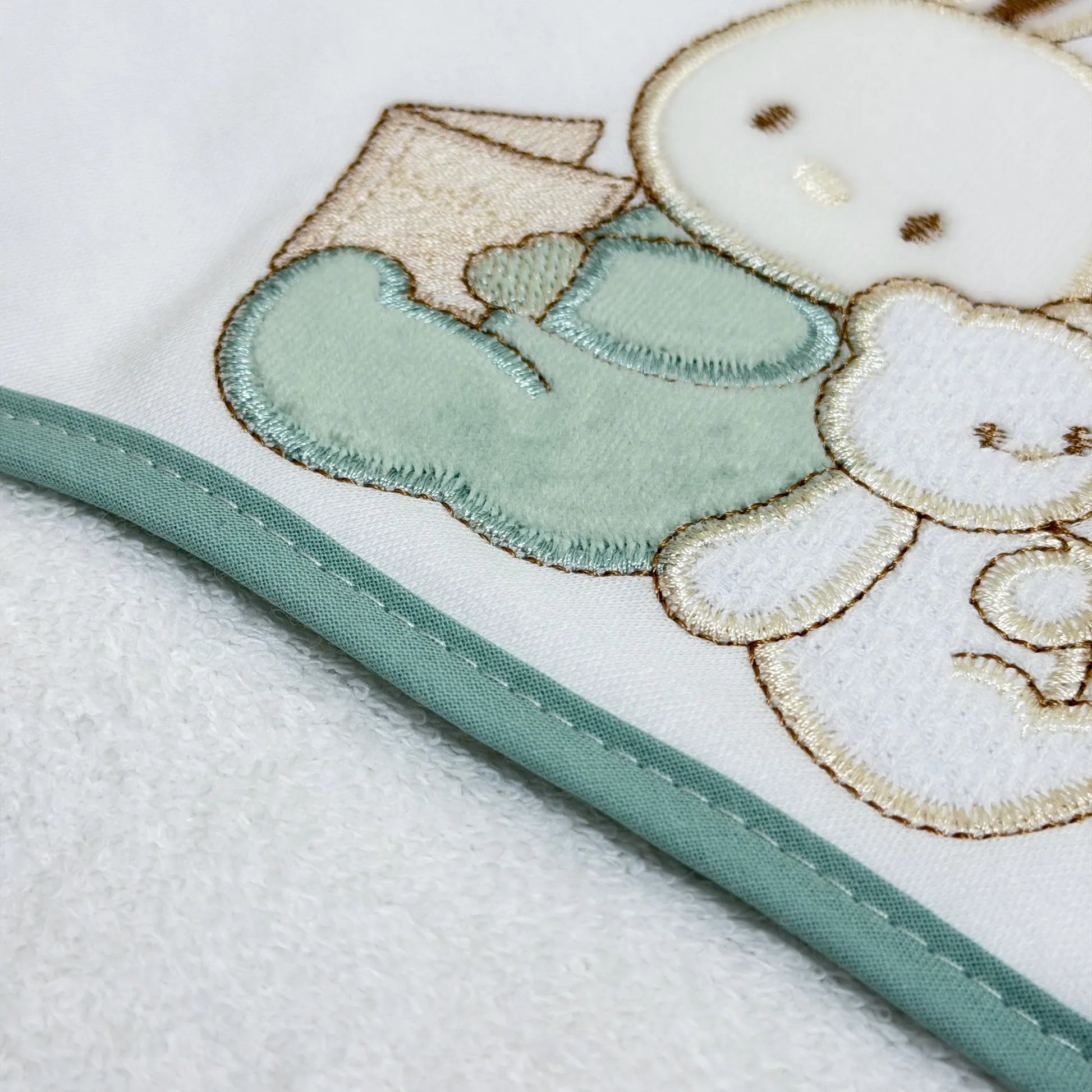 Pormenor de toalha com motivo coelhinho e ursinho com livro verde