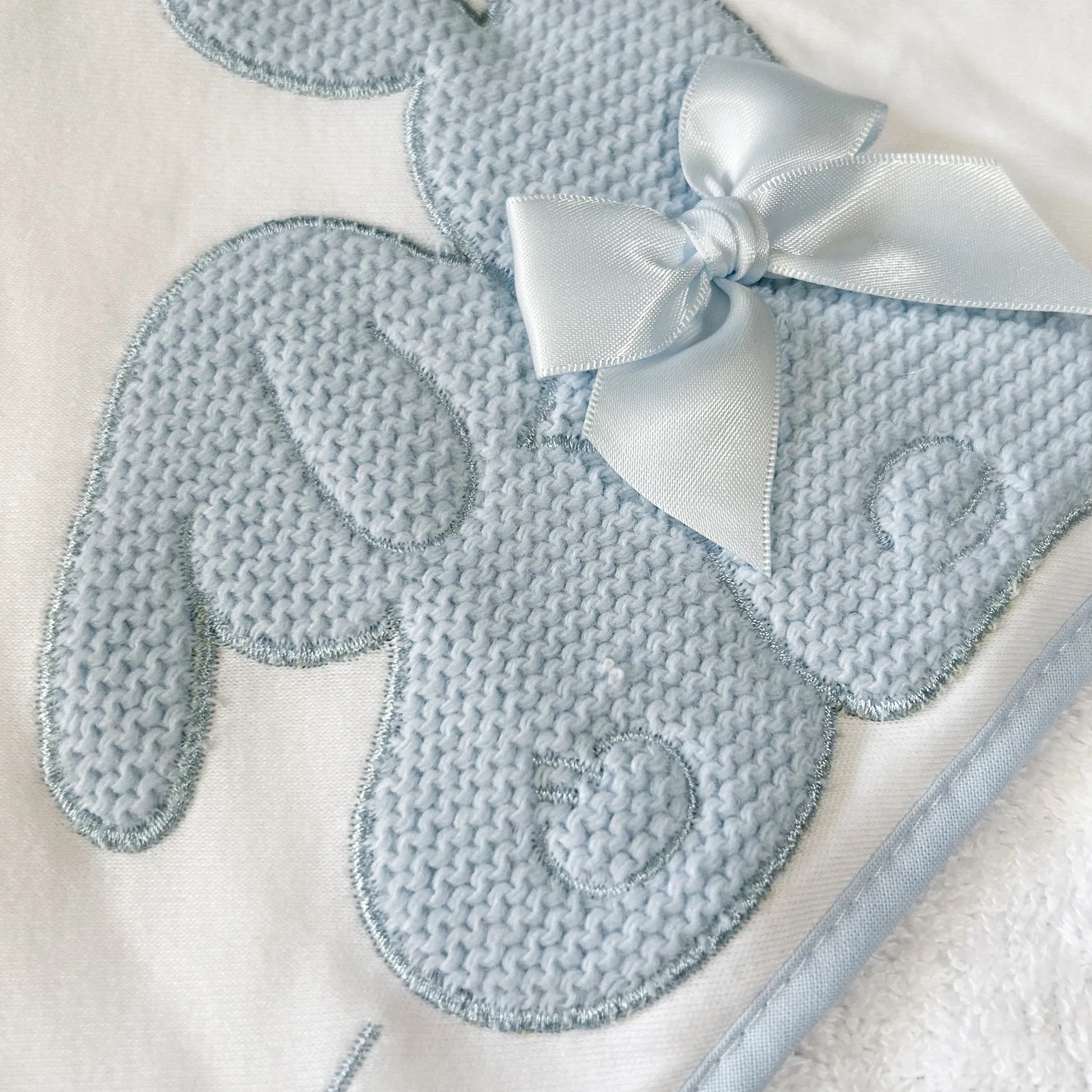Pormenor de toalha com motivo coelhos tricot com laço azul