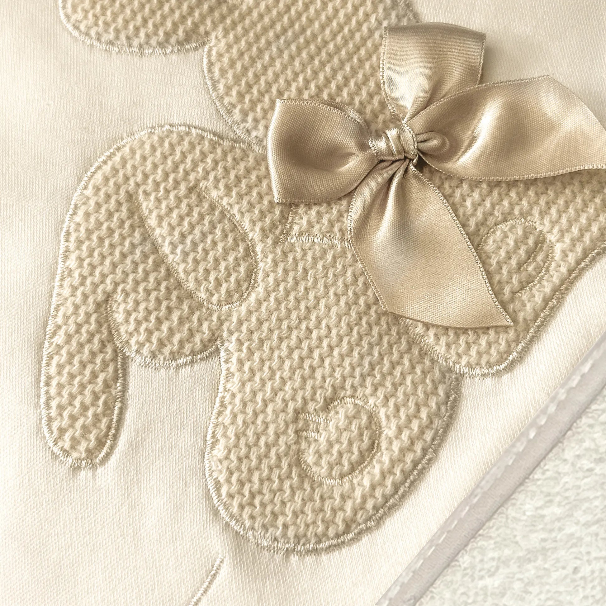 Pormenor de toalha com motivo coelhos tricot com laço bege