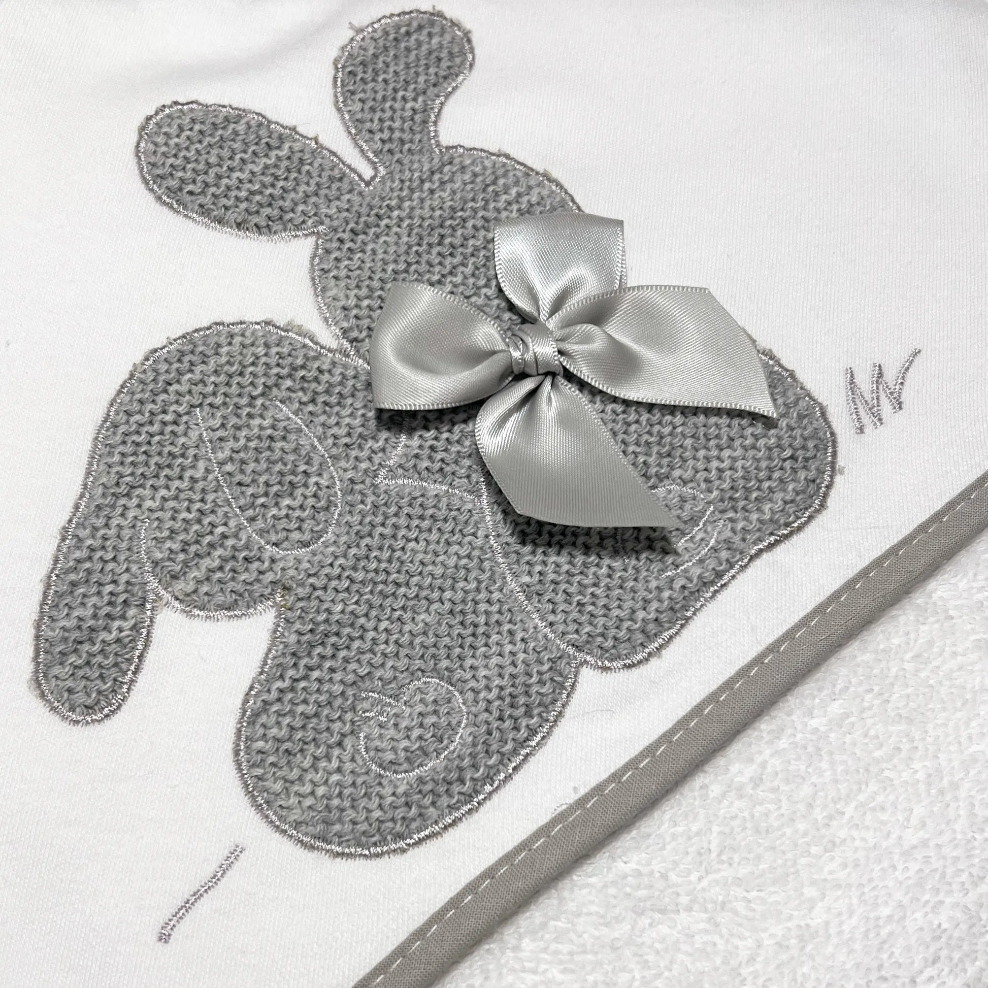 Pormenor de toalha com motivo coelhos tricot com laço cinza