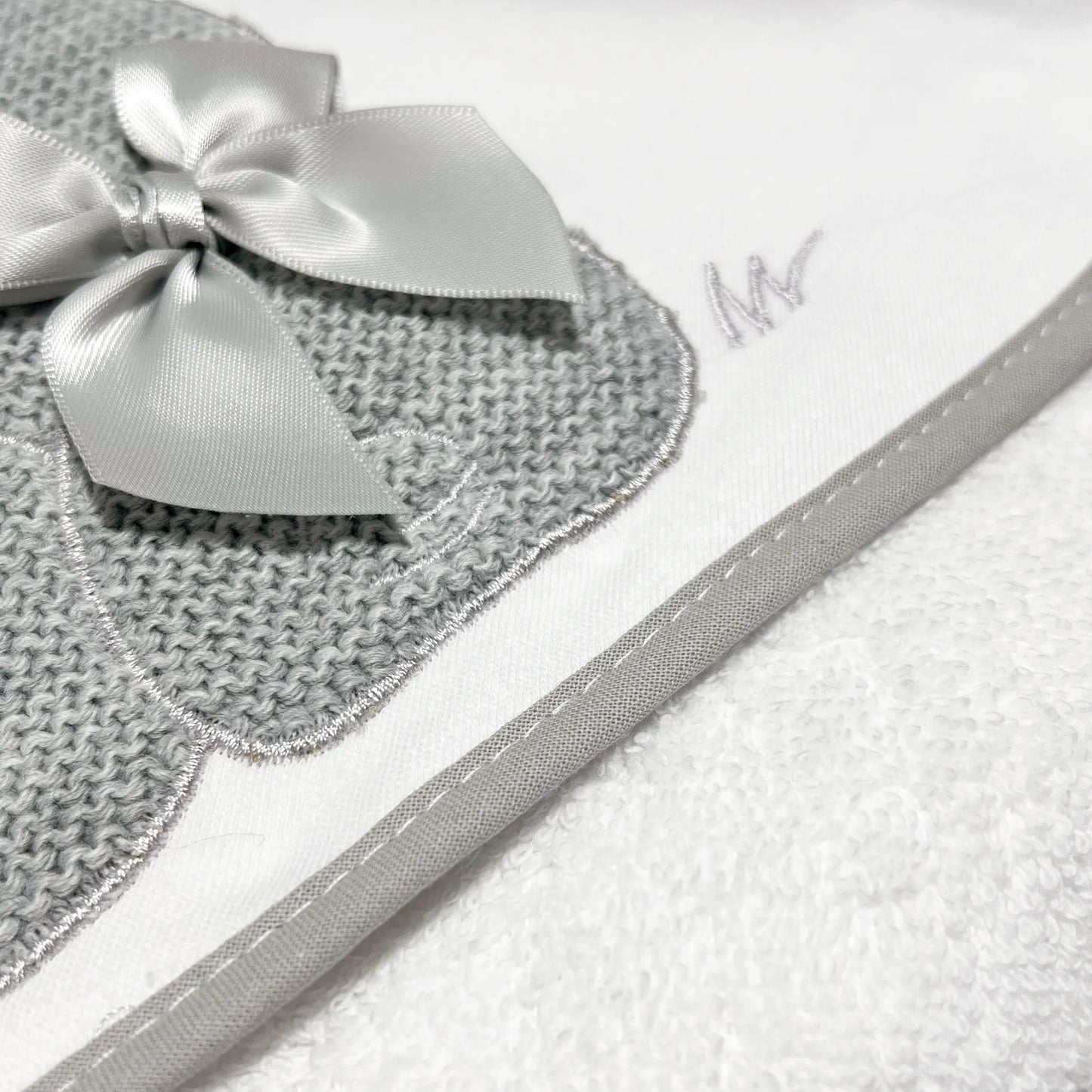 Pormenor de toalha com motivo coelhos tricot com laço cinza