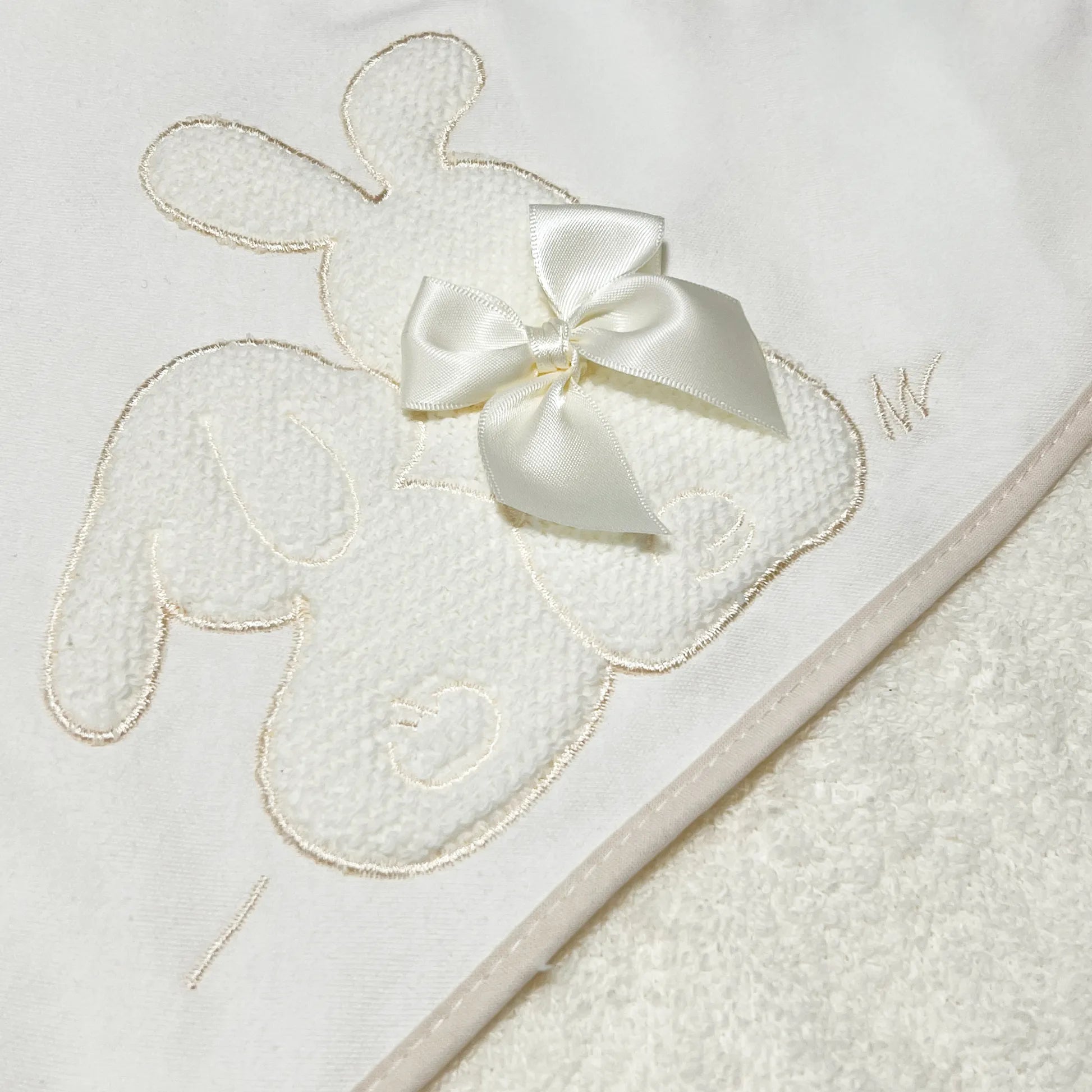 Pormenor de toalha com motivo coelhos tricot com laço pérola