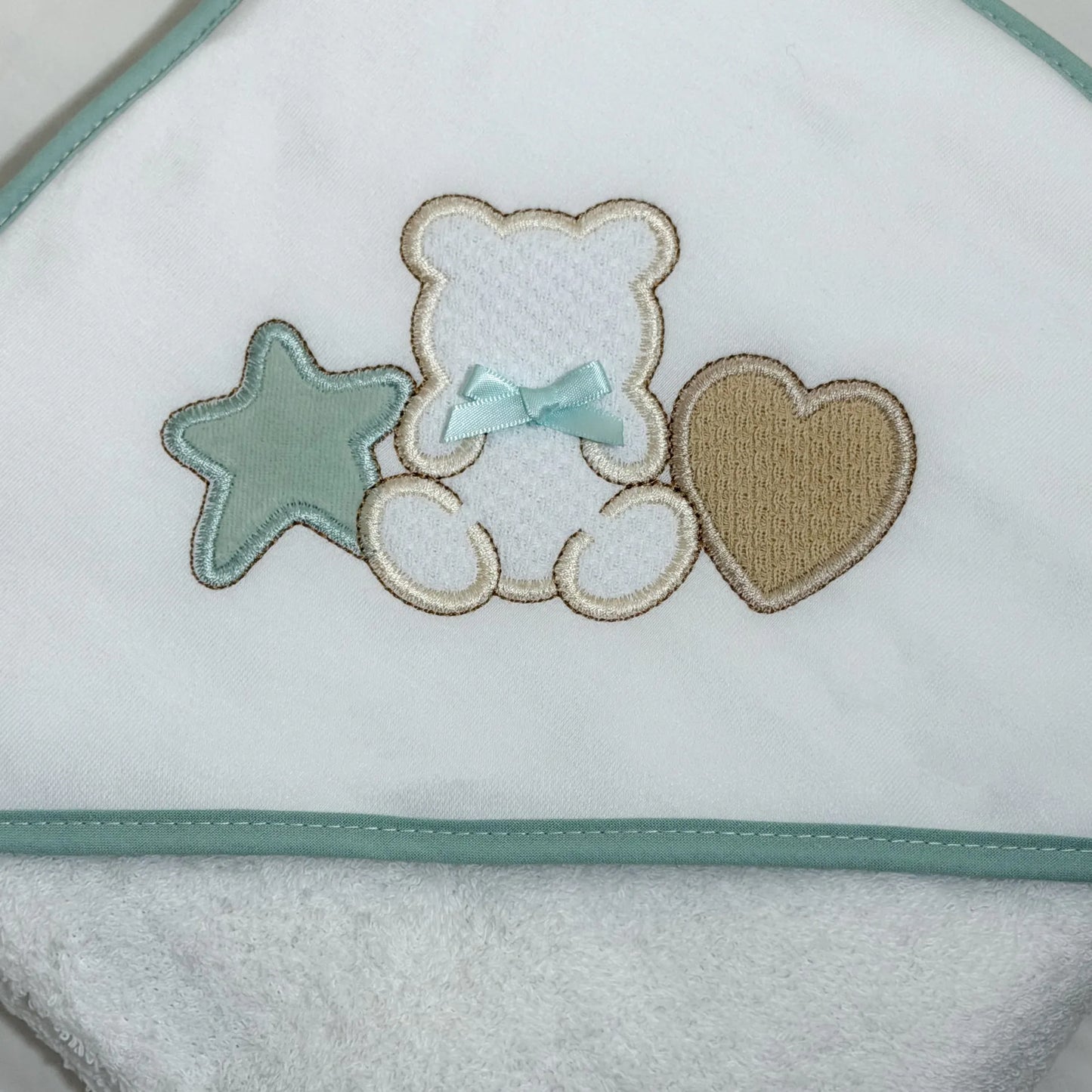 Pormenor de toalha com motivo ursinho entre estrela e coração verde