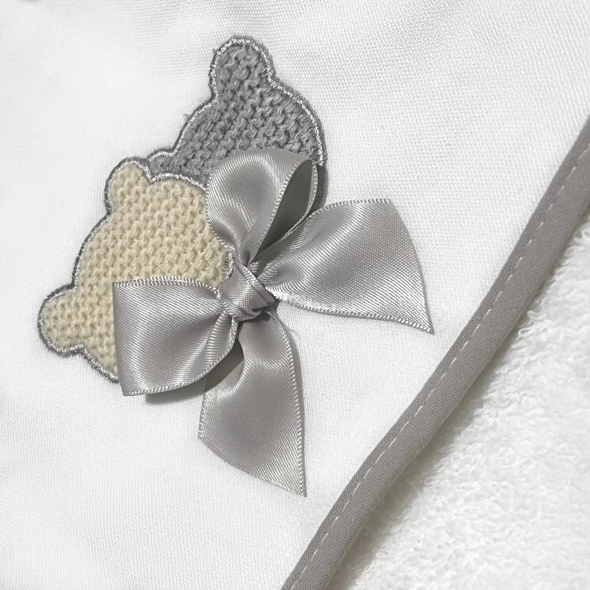 Pormenor de toalha com motivo ursinhos tricot e laço cinza