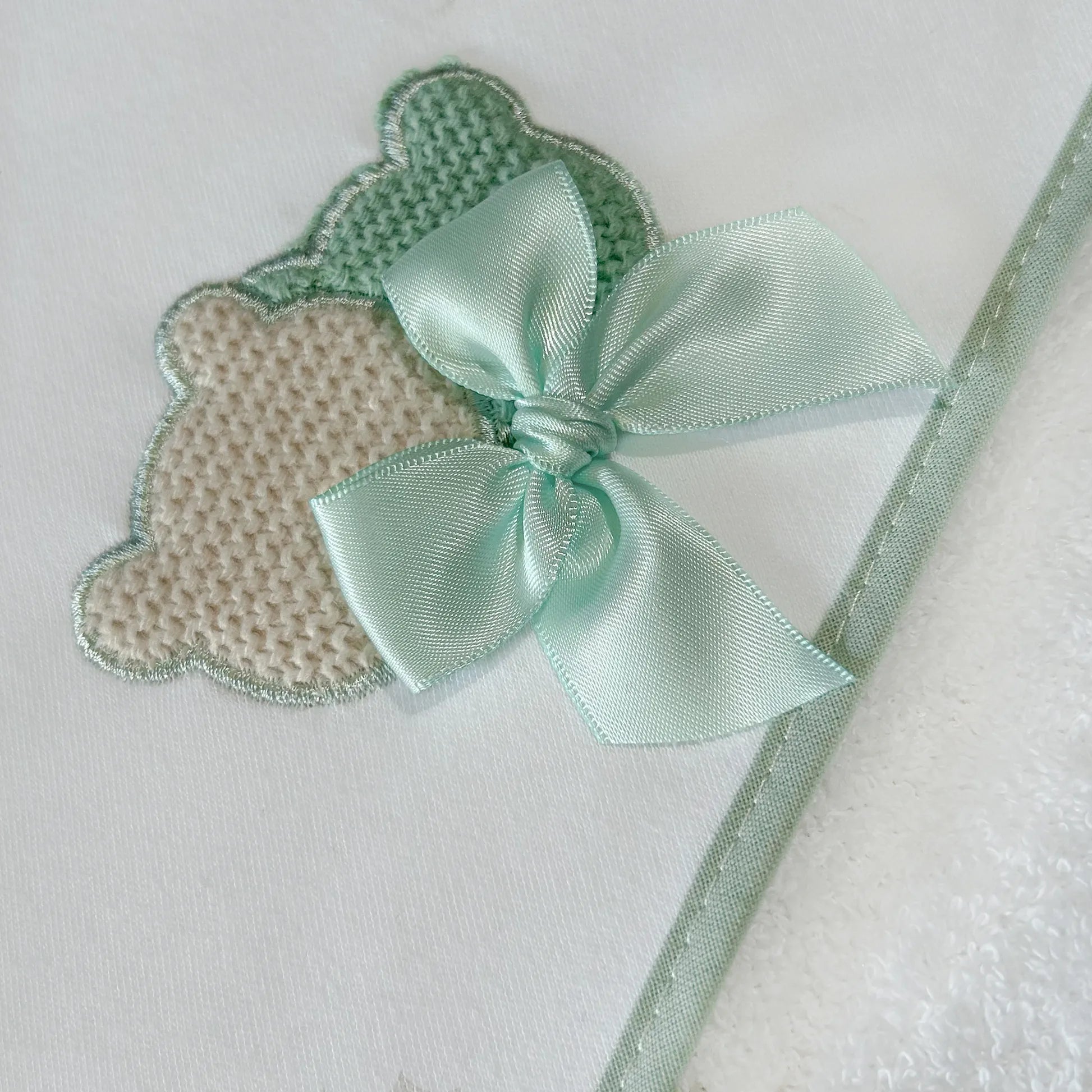 Pormenor de toalha com motivo ursinhos tricot e laço verde