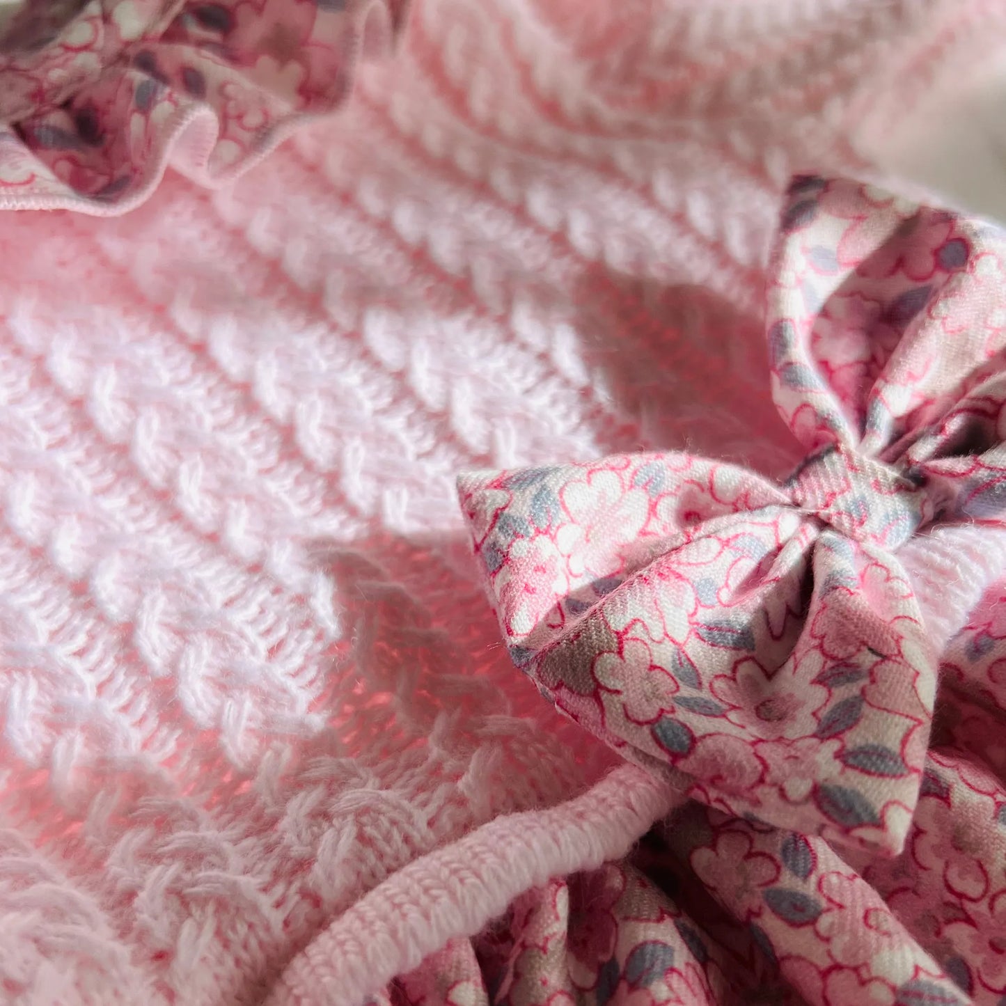 Pormenor de vestido estampado com folho na gola e laço na cintura rosa