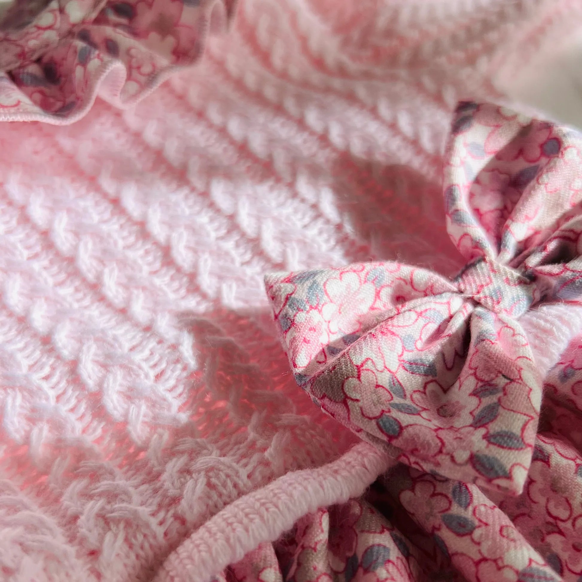 Pormenor de vestido estampado com folho na gola e laço na cintura rosa