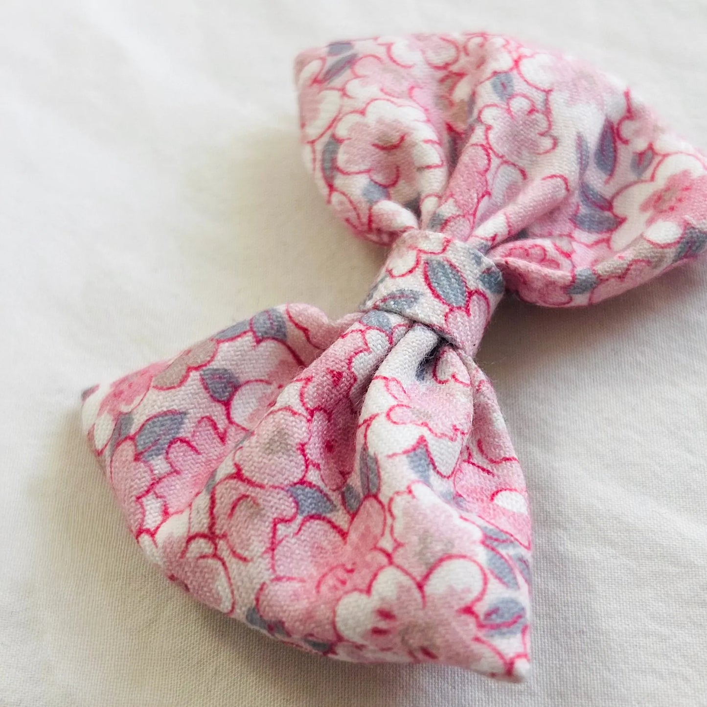 Pormenor de vestido estampado com folho na gola e laço na cintura rosa